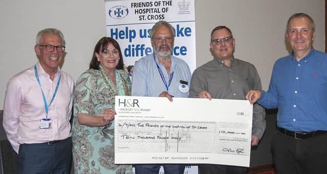 Image of Hinckley & Rugby Building Society CEO Colin Fyfe and others holding a big cheque at Rugby’s Hospital of St Cross.